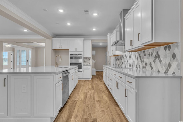 kitchen with white cabinetry, sink, stainless steel appliances, a center island with sink, and ornamental molding