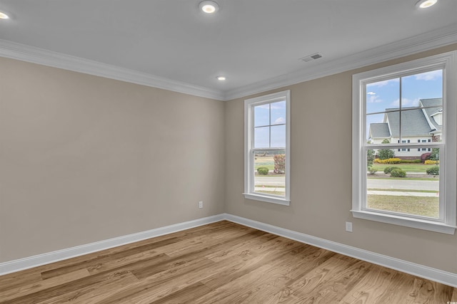 empty room with light hardwood / wood-style floors, plenty of natural light, and crown molding