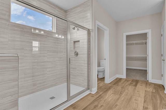 bathroom with toilet, a shower with door, and hardwood / wood-style flooring