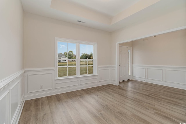 unfurnished room with a raised ceiling and light hardwood / wood-style flooring