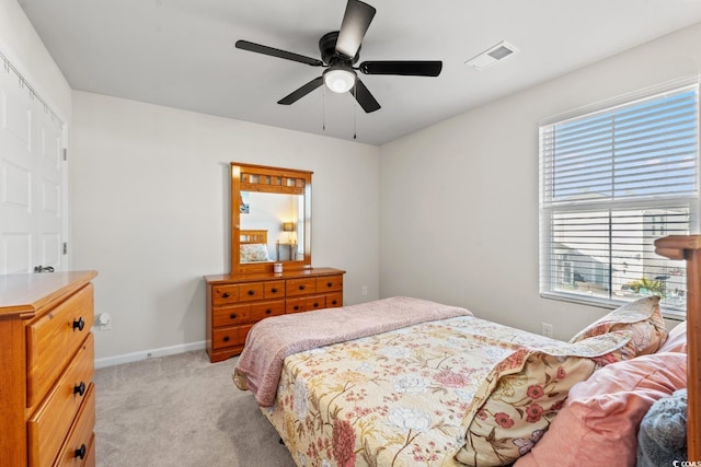 bedroom featuring ceiling fan, multiple windows, and light carpet