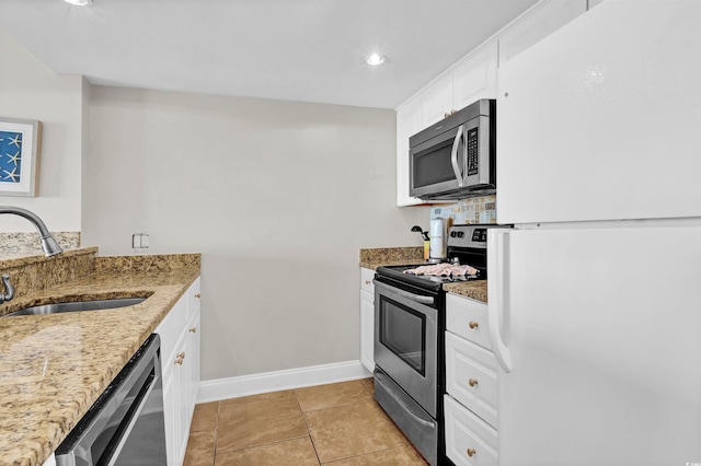 kitchen with light stone countertops, stainless steel appliances, sink, light tile patterned floors, and white cabinetry