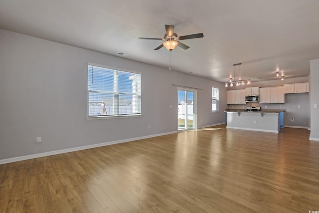 unfurnished living room with light hardwood / wood-style flooring and ceiling fan