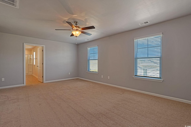 carpeted empty room with a wealth of natural light and ceiling fan