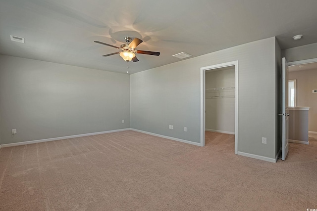 unfurnished bedroom featuring a closet, ceiling fan, a spacious closet, and light colored carpet