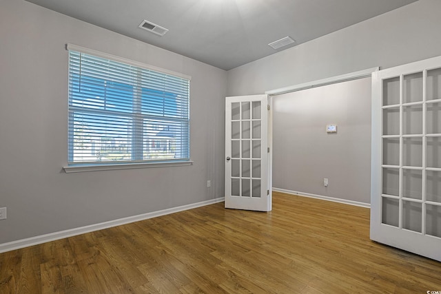 empty room with french doors and hardwood / wood-style floors