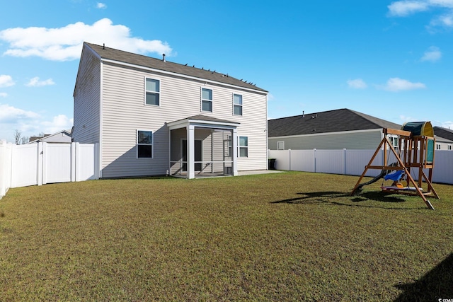 rear view of property featuring a playground, a yard, and a sunroom