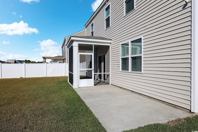 rear view of house with a lawn, a patio area, and a sunroom