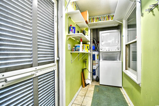 clothes washing area featuring light tile patterned flooring and stacked washer / dryer