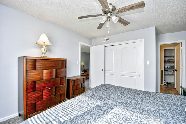 carpeted bedroom featuring a textured ceiling, a closet, and ceiling fan