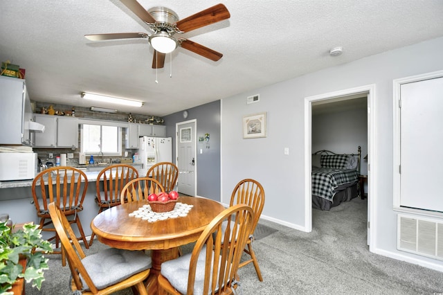 dining space with a textured ceiling, light colored carpet, ceiling fan, and sink