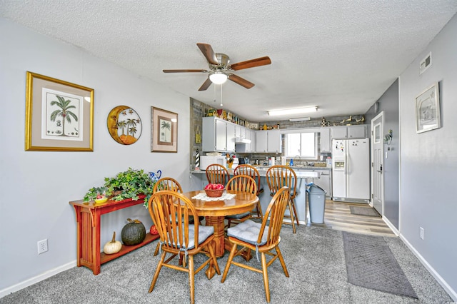 dining space featuring ceiling fan, light carpet, and a textured ceiling