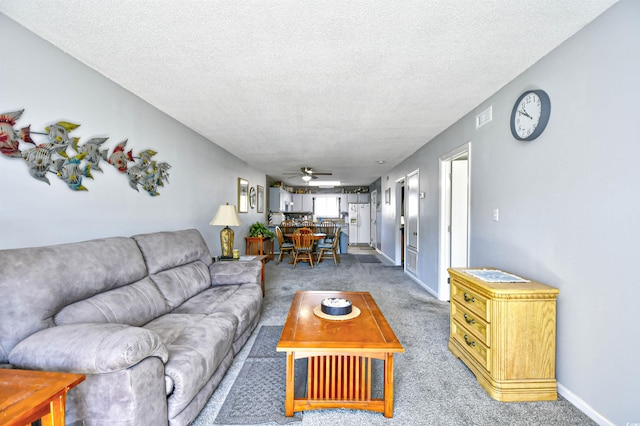 living room with carpet, ceiling fan, and a textured ceiling