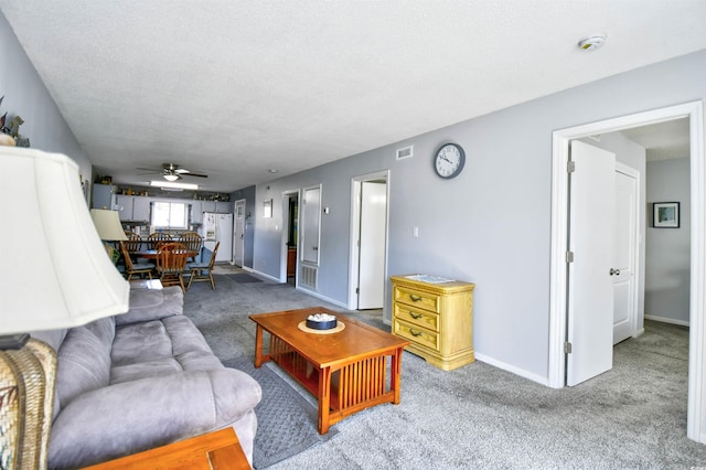 carpeted living room featuring ceiling fan and a textured ceiling