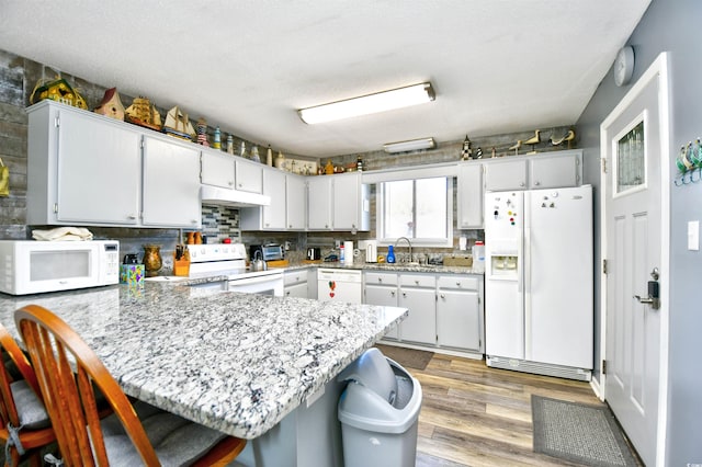 kitchen featuring kitchen peninsula, a breakfast bar, and white appliances