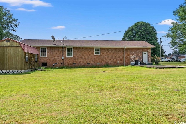 rear view of house featuring a storage unit and a lawn