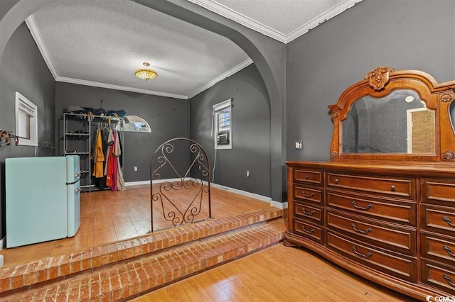 interior space with wood-type flooring, white refrigerator, a textured ceiling, and ornamental molding