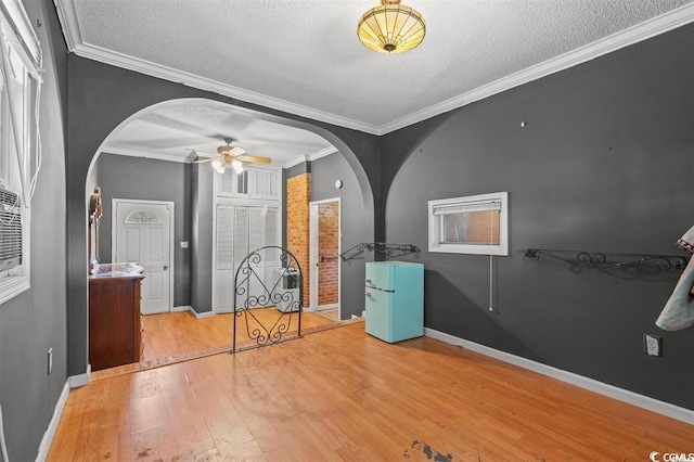 interior space featuring a textured ceiling, light hardwood / wood-style flooring, and crown molding