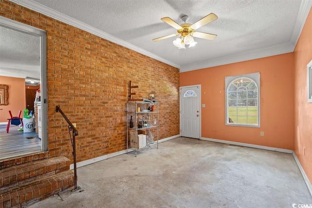 interior space with a textured ceiling, ceiling fan, crown molding, and brick wall