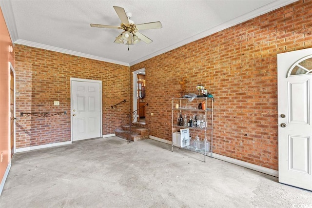 entryway with ceiling fan, ornamental molding, a textured ceiling, and brick wall