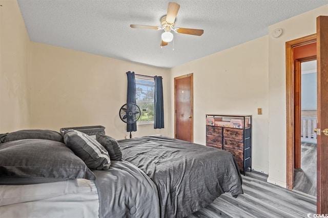 bedroom with ceiling fan, a textured ceiling, and light hardwood / wood-style flooring