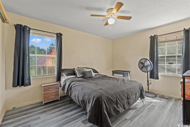 bedroom featuring wood-type flooring, a textured ceiling, and ceiling fan