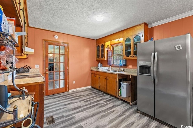 kitchen with stainless steel fridge, crown molding, and light hardwood / wood-style flooring