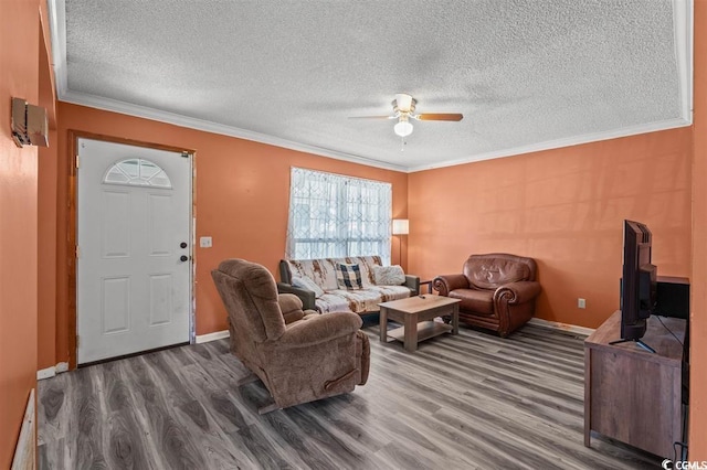 living room with ceiling fan, wood-type flooring, a textured ceiling, and ornamental molding