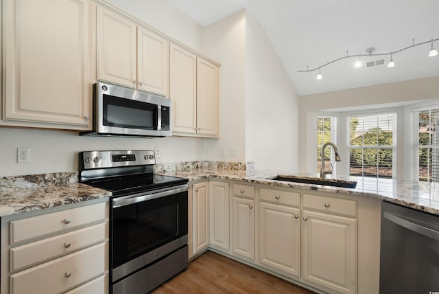 kitchen with lofted ceiling, sink, light hardwood / wood-style floors, kitchen peninsula, and stainless steel appliances