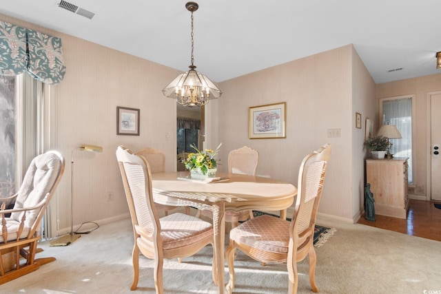 dining space with a chandelier and light carpet