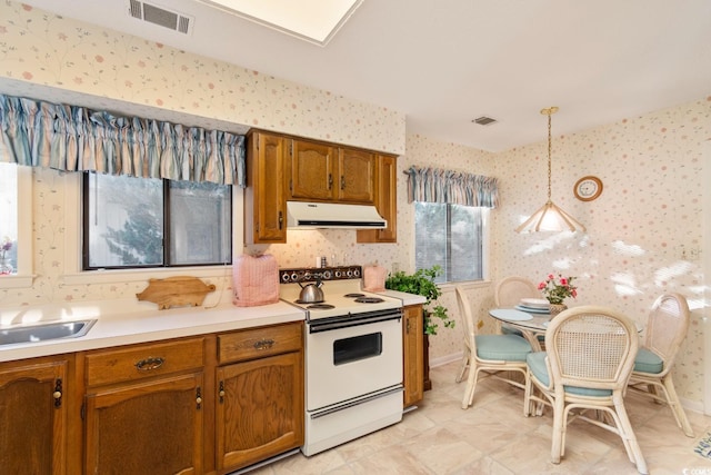 kitchen with white electric stove, hanging light fixtures, and sink