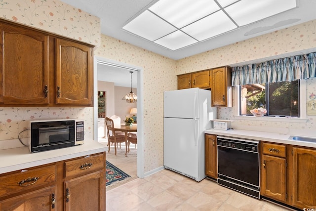 kitchen featuring white refrigerator, black dishwasher, hanging light fixtures, and an inviting chandelier