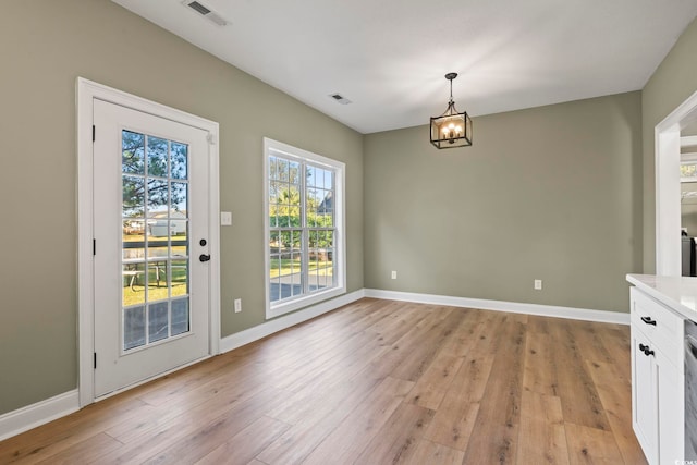 unfurnished dining area featuring light wood-type flooring and an inviting chandelier