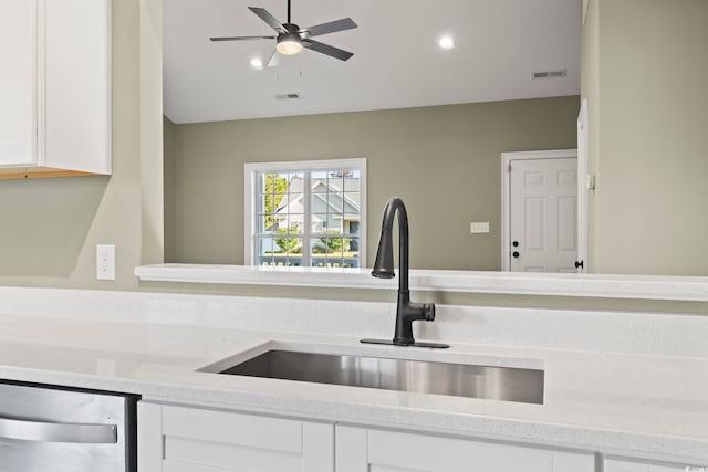 kitchen featuring dishwasher, sink, white cabinets, and light stone counters