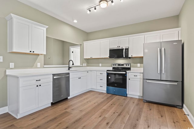 kitchen with white cabinets, appliances with stainless steel finishes, and light hardwood / wood-style flooring