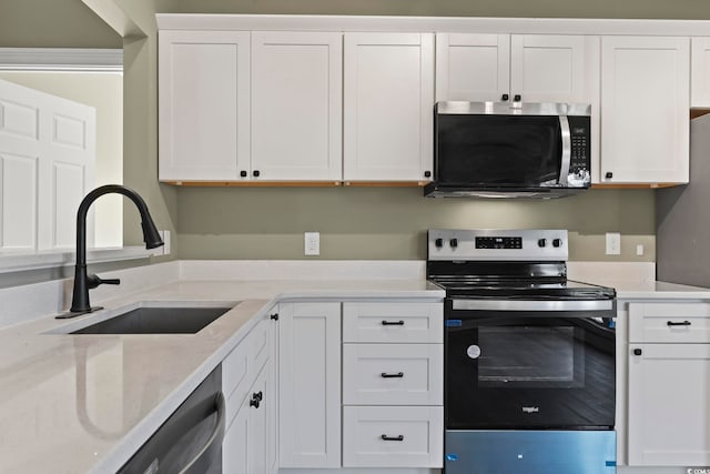 kitchen featuring white cabinetry, sink, light stone countertops, and appliances with stainless steel finishes