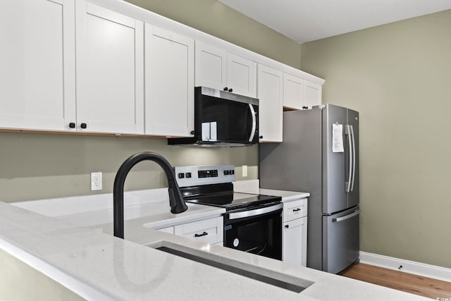 kitchen with white cabinetry, stainless steel appliances, and wood-type flooring