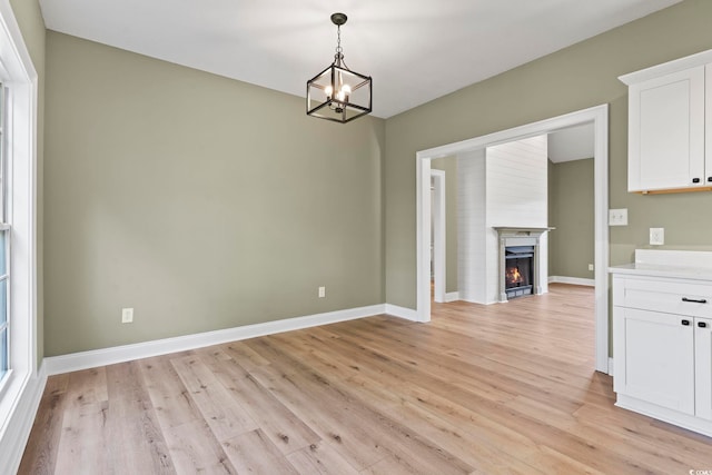 unfurnished dining area with plenty of natural light, light hardwood / wood-style floors, and an inviting chandelier