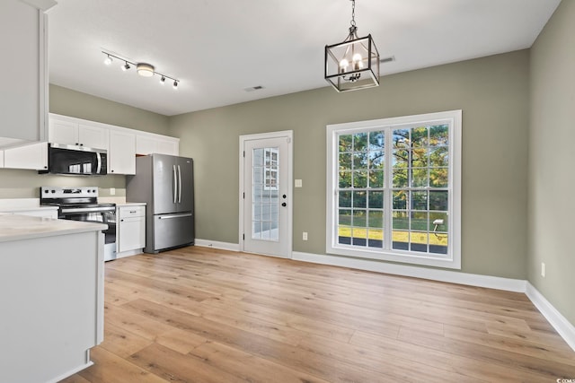 kitchen featuring white cabinets, appliances with stainless steel finishes, decorative light fixtures, and light hardwood / wood-style flooring