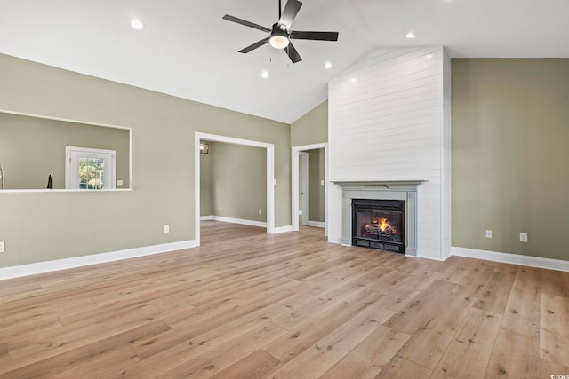 unfurnished living room featuring a large fireplace, high vaulted ceiling, light hardwood / wood-style flooring, and ceiling fan