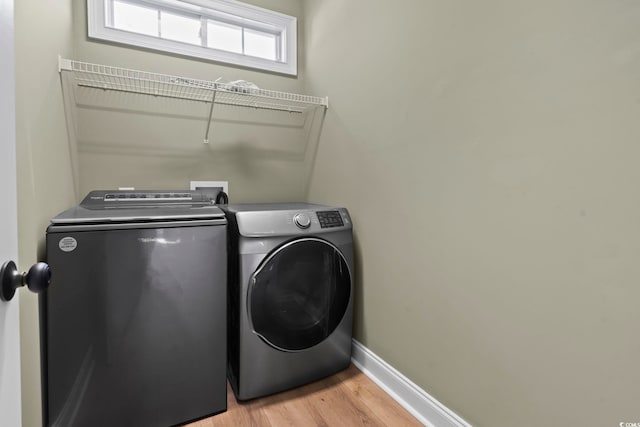 laundry room featuring washer and clothes dryer and light hardwood / wood-style flooring