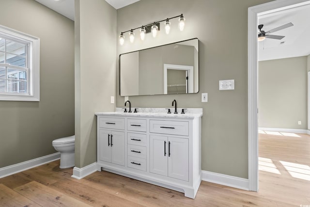 bathroom with hardwood / wood-style floors, vanity, toilet, and ceiling fan