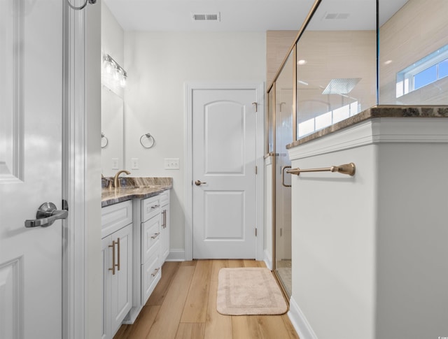 bathroom featuring hardwood / wood-style flooring, vanity, and a shower with shower door