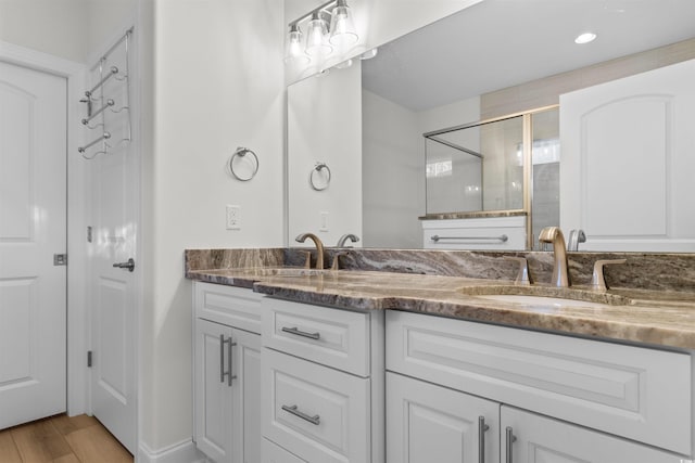 bathroom with wood-type flooring, vanity, and a shower with door