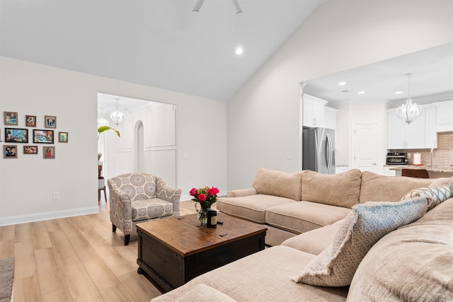 living room with light hardwood / wood-style flooring, high vaulted ceiling, and a notable chandelier