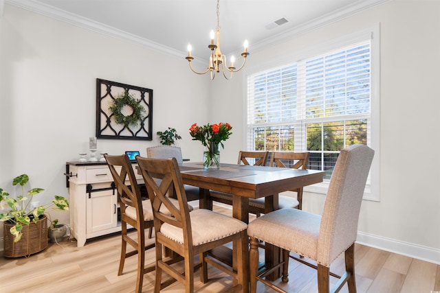 dining room featuring light hardwood / wood-style floors, crown molding, and a notable chandelier