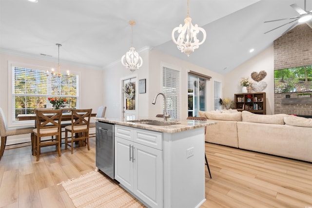 kitchen featuring stainless steel dishwasher, sink, pendant lighting, a center island with sink, and white cabinetry