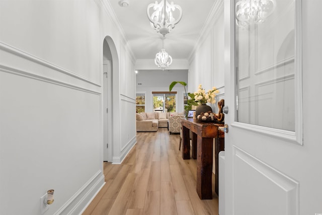 hall with a chandelier, light hardwood / wood-style floors, and crown molding