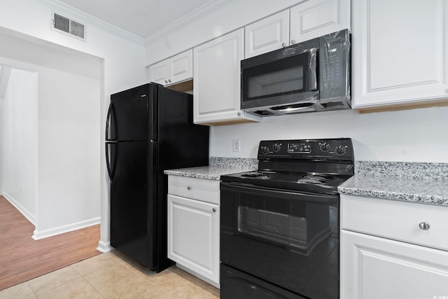 kitchen with light stone countertops, light hardwood / wood-style floors, white cabinets, black appliances, and ornamental molding