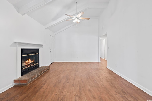 unfurnished living room with ceiling fan, beam ceiling, wood-type flooring, and a fireplace